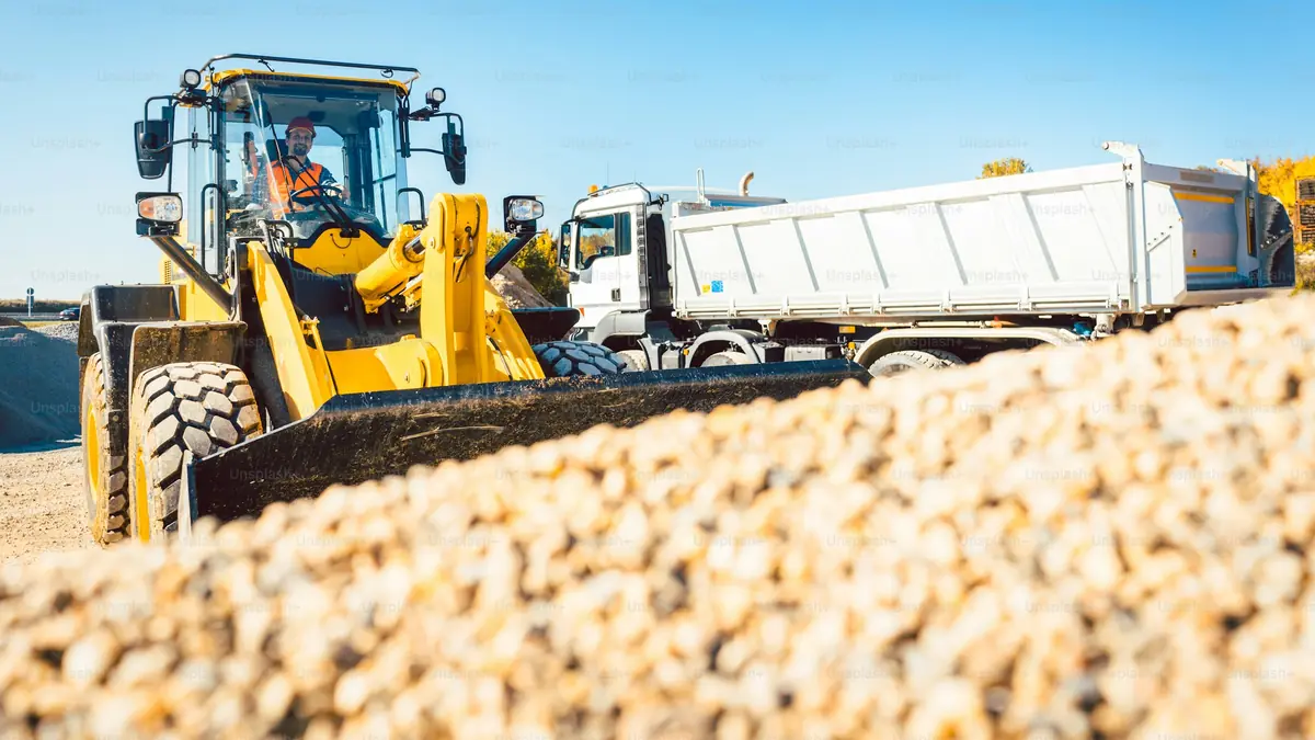 Wheel loader filling a tipper truck with graded aggregate on a construction site