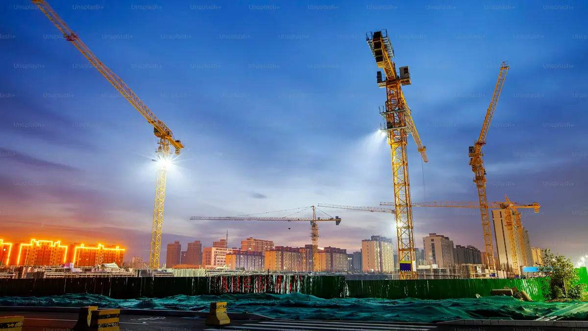 Tower cranes working over a construction site at dusk